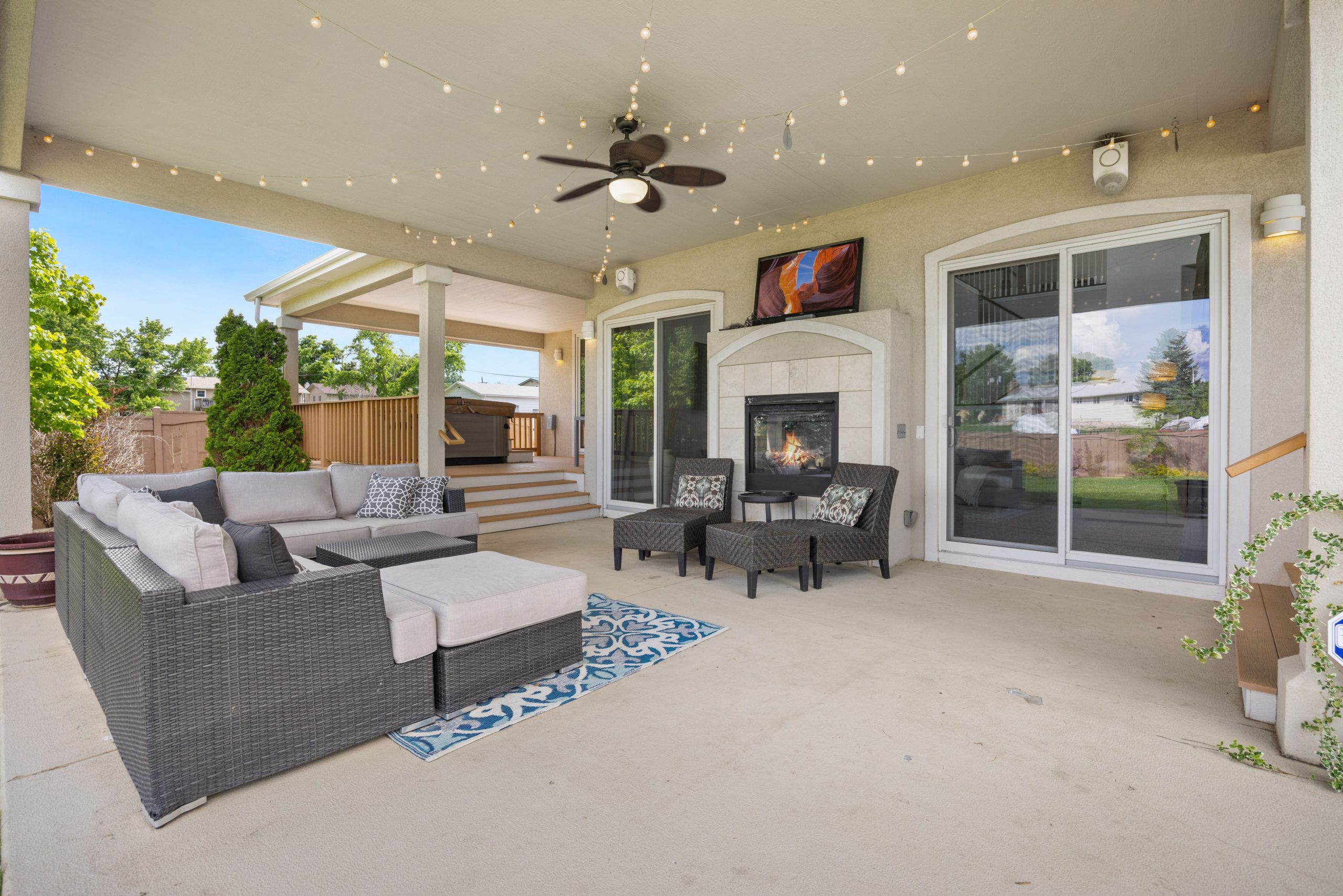 Luxurious outdoor patio with a cozy fireplace, modern lounge furniture, and ambient string lights